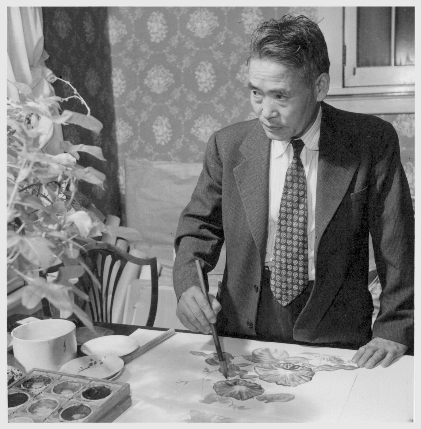A man in a suit holds a calligraphy brush