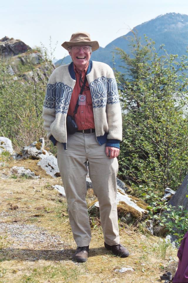 Jason Morgan laughs from a hiking trail with mountains behind him.